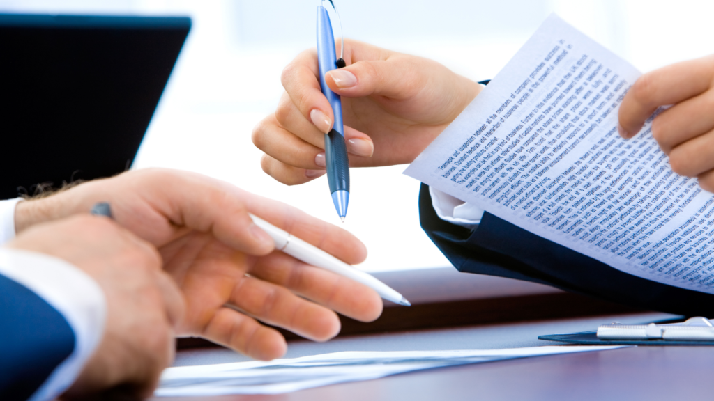 two set of hands, both holding pens, one person holding paper work - adam tobin law