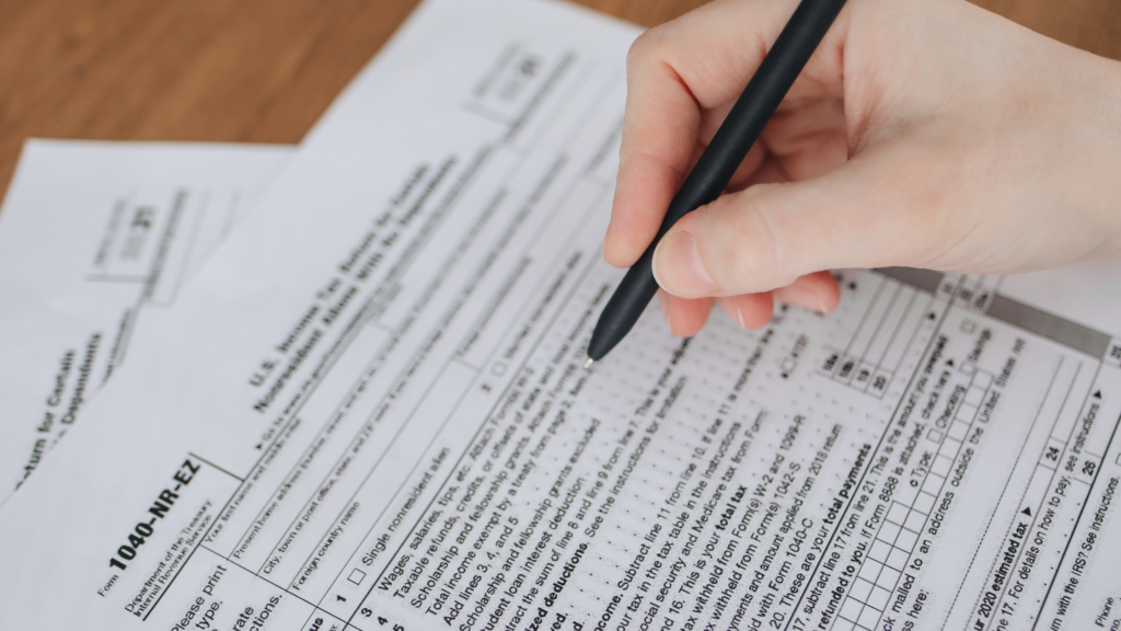 Tax paperwork with a person filling it out with a black pen - adam tobin law 